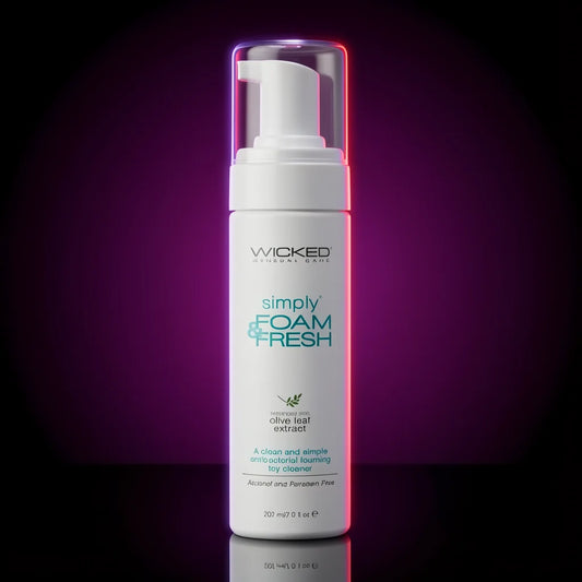 A white pump bottle of Wicked London Simply Foam + Fresh anti-foaming liquid with olive leaf extract, set against a dark background with a purple and pink glow.
