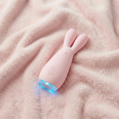 Pink dual motor bunny vibrator with glowing blue LED light displayed on soft pink fleece blanket