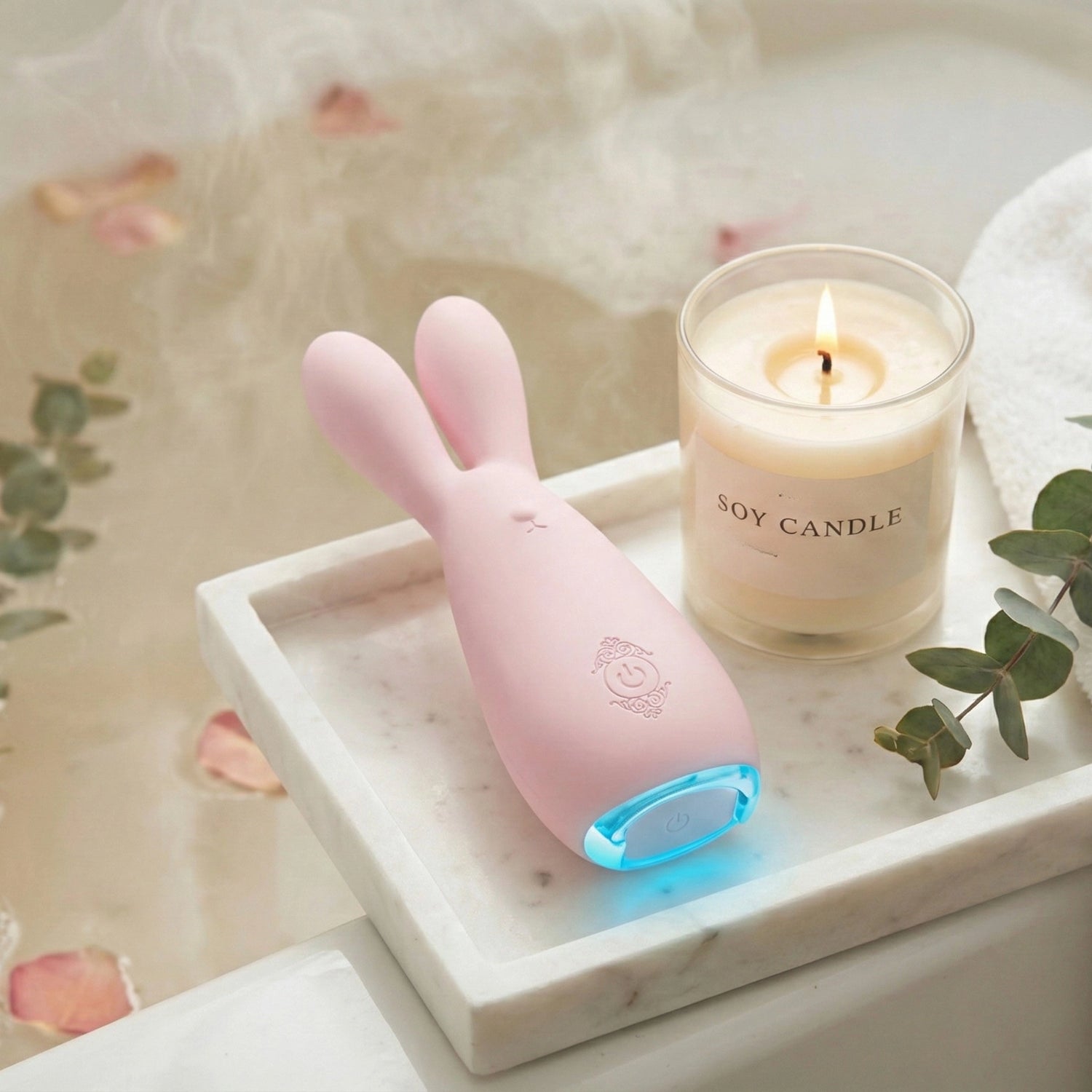 Pink waterproof bunny rabbit vibrator with LED light on marble bath tray with soy candle, eucalyptus, rose petals