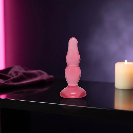 Translucent pink jelly plug standing on a dark shelf