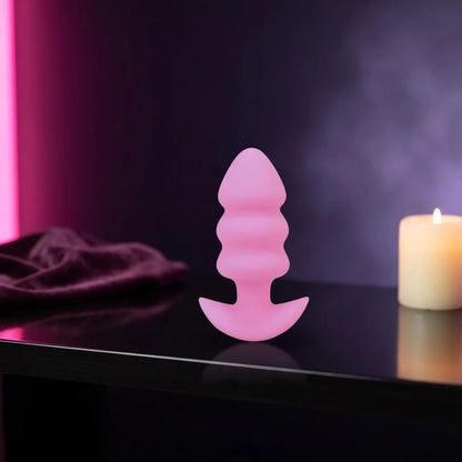 Pink ribbed vibrating micro plug on a dark shelf