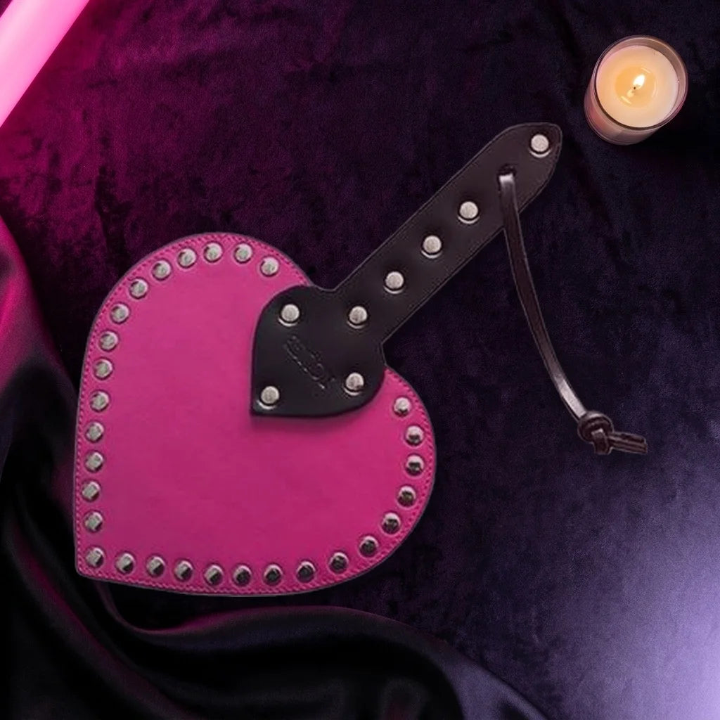 Hot pink studded heart paddle on dark purple velvet
